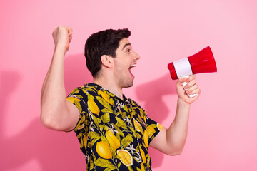 Fashionable young man with a megaphone expressing excitement on a pink background, promoting...