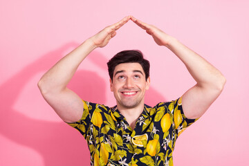 Young man wearing a tropical print shirt making a cheerful gesture against a trendy pink background...