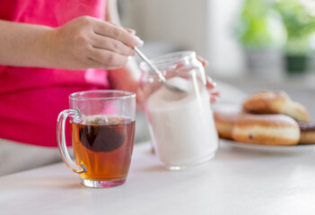 Close-Up Of A Woman Adding Sugar Into Tea