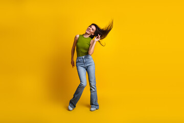 Cheerful young woman in casual wear enjoying a joyful moment in front of a vibrant yellow background