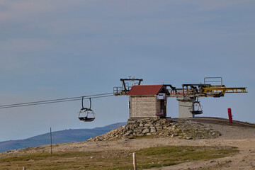 Empty chairlift over green mountain landscape.