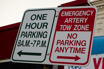 Outdoor parking signs on single post, one for limited time parking and the other for emergency artery tow zone with no parking anytime, clear and directive instructions