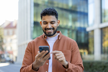 Smiling person using a smartphone outdoors in an urban setting