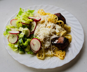 Vibrant pasta salad featuring fusilli, sauerkraut, fresh lettuce, and sliced radishes. Topped with...