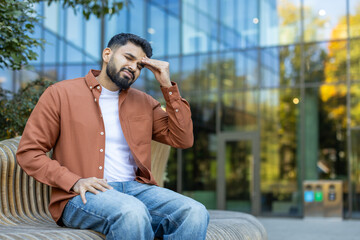 Man sitting outdoors with a headache in an urban environment