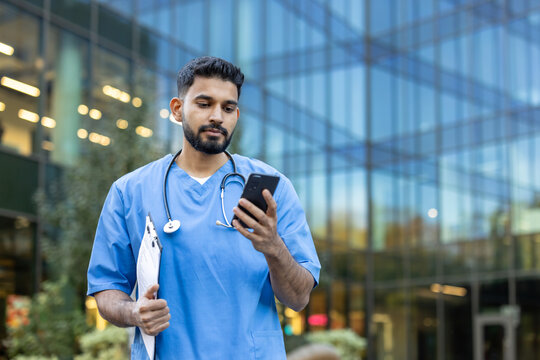 Healthcare worker checking phone while outside a modern building