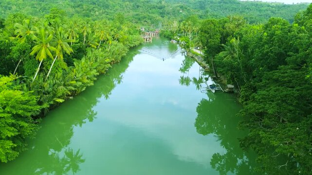 Aerial view of traditional stilt houses and boats amidst dense tropical forest along the Amazon River.