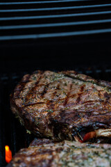 Well grilled huge steak on BBQ gas grill searing hot with grill marks crossed, and lots of seasoning.