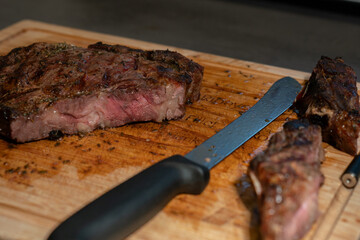 Sliced steak on cutting board with knife laying in the middle.