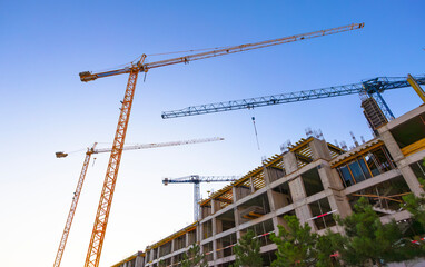 Construction of a new residential area using high-rise cranes at sunset.