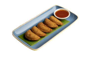 Prawns Rissois (Rissois de Camarão) — Crispy Portuguese pastry filled with creamy prawn ragout, served on a banana leaf with dipping sauce in a white bowl on a blue plate. PNG isolated.