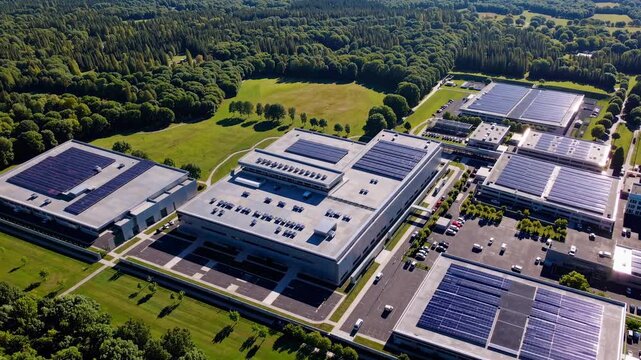 Aerial video view of a modern industrial complex with solar panels, surrounded by lush greenery, showcasing sustainability from above.