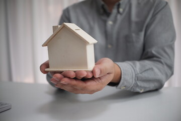 Real estate agent and customer signing a contract, buying a new home, model house in the foreground