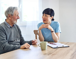 Doctor or nurse caregiver with senior couple at home or nursing home