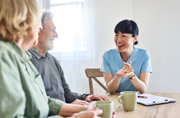 Doctor or nurse caregiver with senior couple at home or nursing home