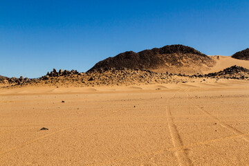 The landscape of the Sahara. A rocky desert, sandy dunes, and bizarre rocky mountains. El Berdj...