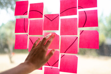 Woman composing heart shape with pink sticky notes on window