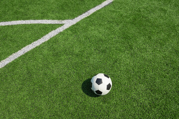 Soccer ball on green grass field with white line. Football stadium background.