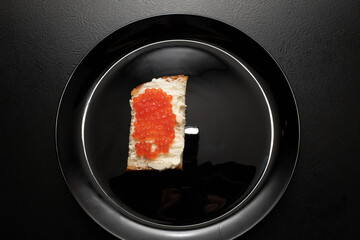 Red salmon caviar sandwich. Red coho salmon caviar on a slice of bread with butter. Fish caviar is a protein product for healthy eating.