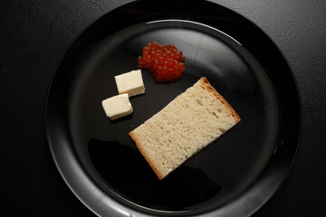 Red salmon caviar sandwich. Red coho salmon caviar on a slice of bread with butter. Fish caviar is a protein product for healthy eating.