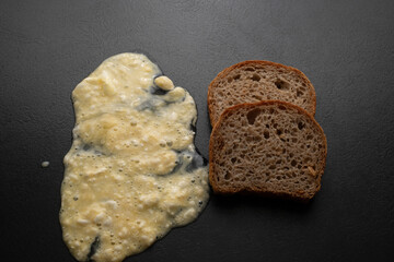 A pile of dough flour and a piece of fresh bread on a black background. Top view. Making dough from...