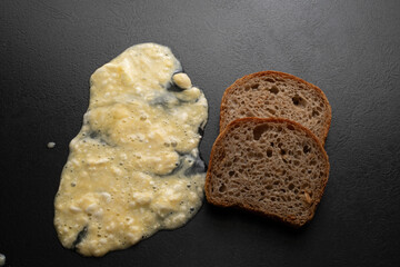 A pile of dough flour and a piece of fresh bread on a black background. Top view. Making dough from...