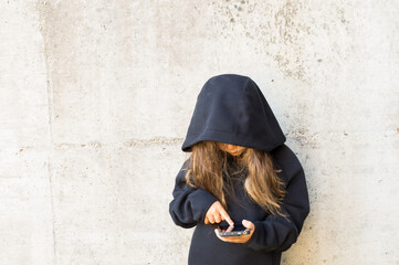 Naklejka premium Teenager in front of a gray wall with a cell phone