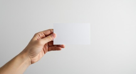 Obraz premium Precise Pinch Grip - A Mans Hand Holding a Virtual Card on a Bright, Minimalist Background.