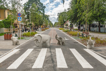 Pedestrian and cycle path featuring elephant sculptures in Parnu, Estonia, Europe. The street is lined with colorful buildings and greenery, creating a charming, artistic atmosphere