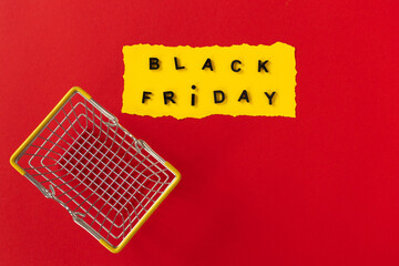 Black friday concept. Top view of yellow torn paper sheet and black friday text in frame on red...