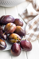 Ripe plums on white table.
