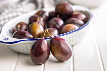 Ripe plums on white table.