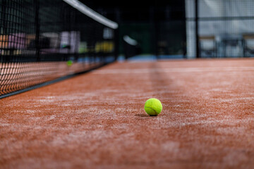 Padel ball resting on court surface during competitive match at sports facility