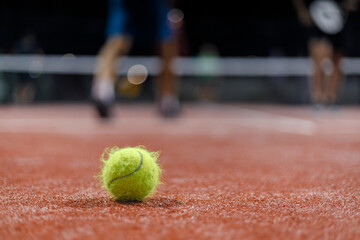 Sport enthusiasts engage in padel tennis on a vibrant red court during an evening match