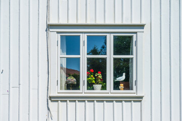 White window with flowerpots and bird figure.