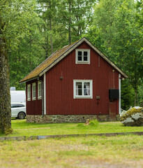 Fototapeta premium Red wooden cottage in lush green forest.