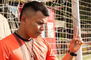 A young Colombian professional coach giving instructions to his players before a training session...