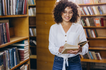 Young student enjoying reading a book in the library