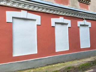 A red facade with plastered and white-painted window openings.