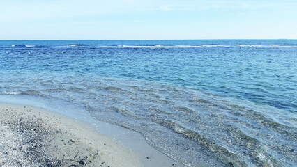 Waves Crashing on Pebble Beach Under a Blue Sky