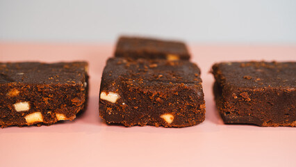 Decadent, fudgy chocolate brownies presented on a vibrant pink and blue background. Ideal for bakery advertising, dessert blogs, or social media content. Professional food photography with bold colors