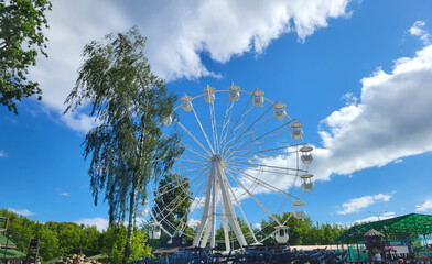 Fototapeta premium A white Ferris wheel against a blue sky in a children's park.