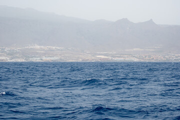 Tranquil ocean waters and distant coastline with misty mountains in the background