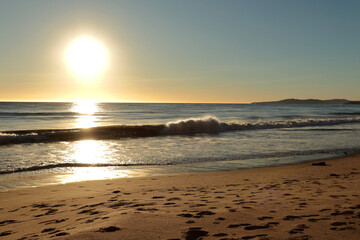 Sunset on the ocean. Footprints are clearly visible in the sand