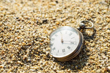 Antique pocket watch lost in the sand. Old watch buried in sand.