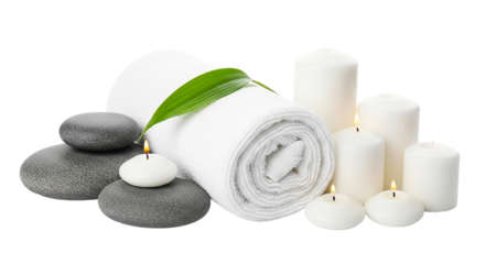 Still life of spa elements featuring a rolled white towel, stones, candles and a green leaf element