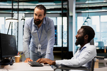 Manager supervising technician in wheelchair using AI on computer to optimize performance and...