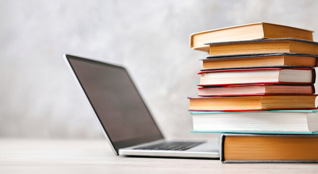 Laptop and stacked books on table illustrating Back to school concept  