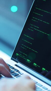 A sleek laptop displaying code on its screen situated in a darkly lit environment