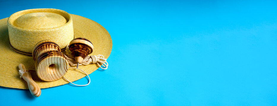 Traditional chilean wooden toys trompo and emboque displayed on a straw hat, suggesting national holidays and Independence Day